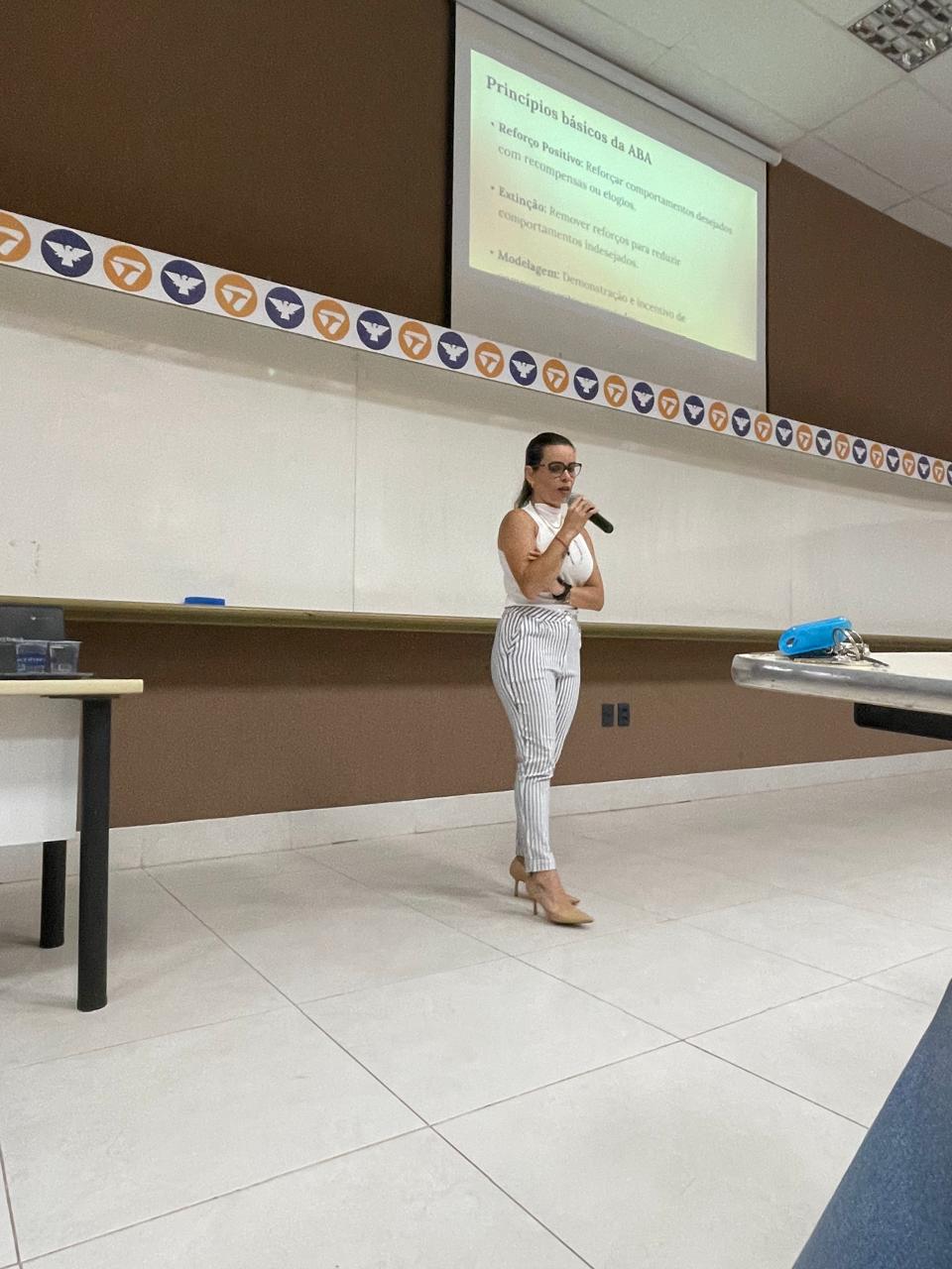 Joice ministrando uma formação com microfone e apresentação projetada